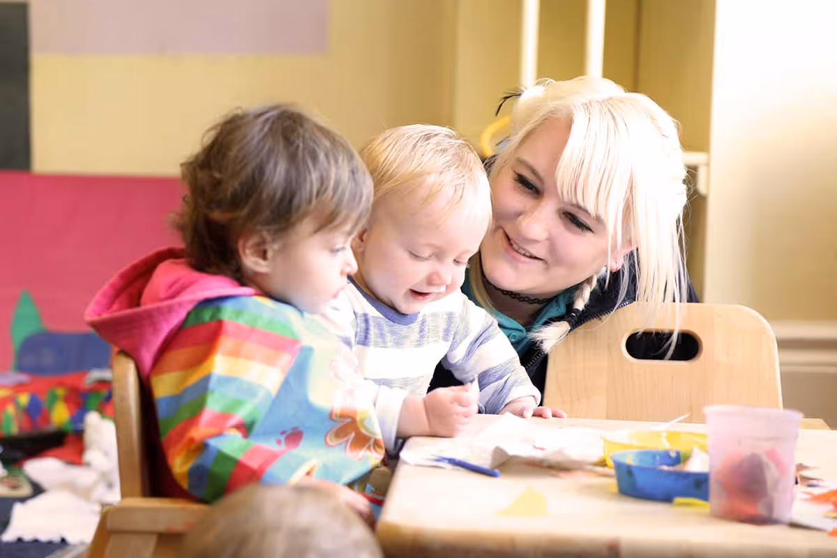 photo of hapy children playing with teacher