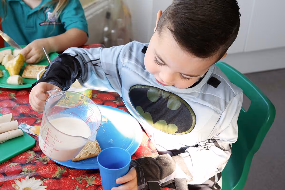 photo of a child pouring some milk