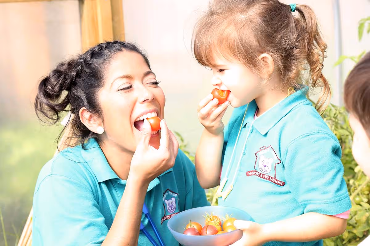 photo of a child and child-minder eating tomatoes