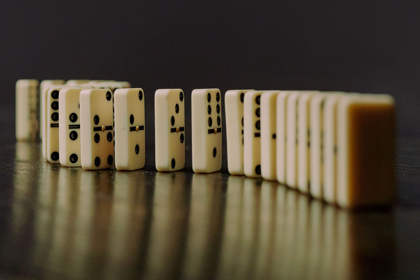 Dominos standing on end and beginning to fall in sequence