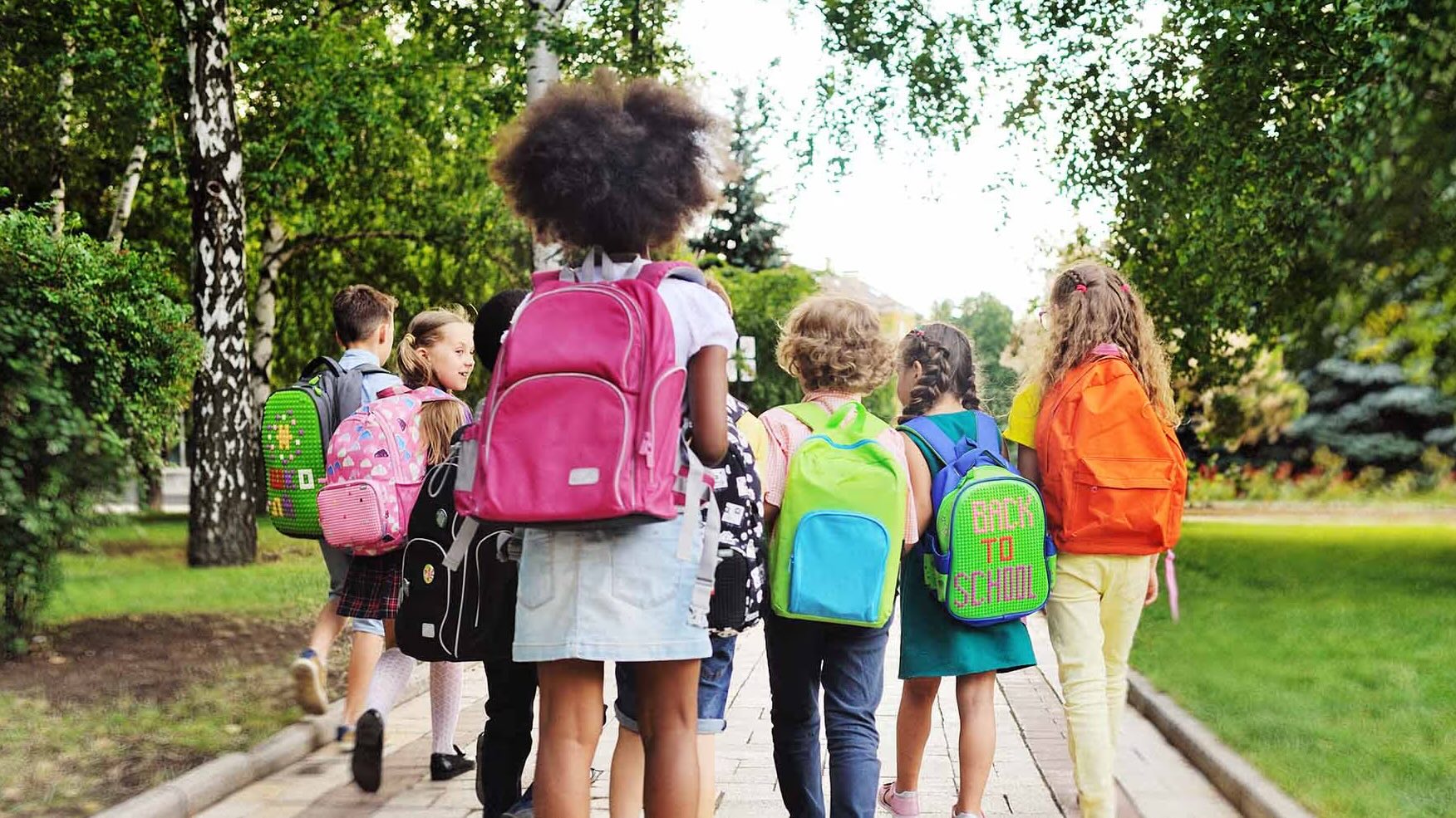 Children returning to school wearing backpacks
