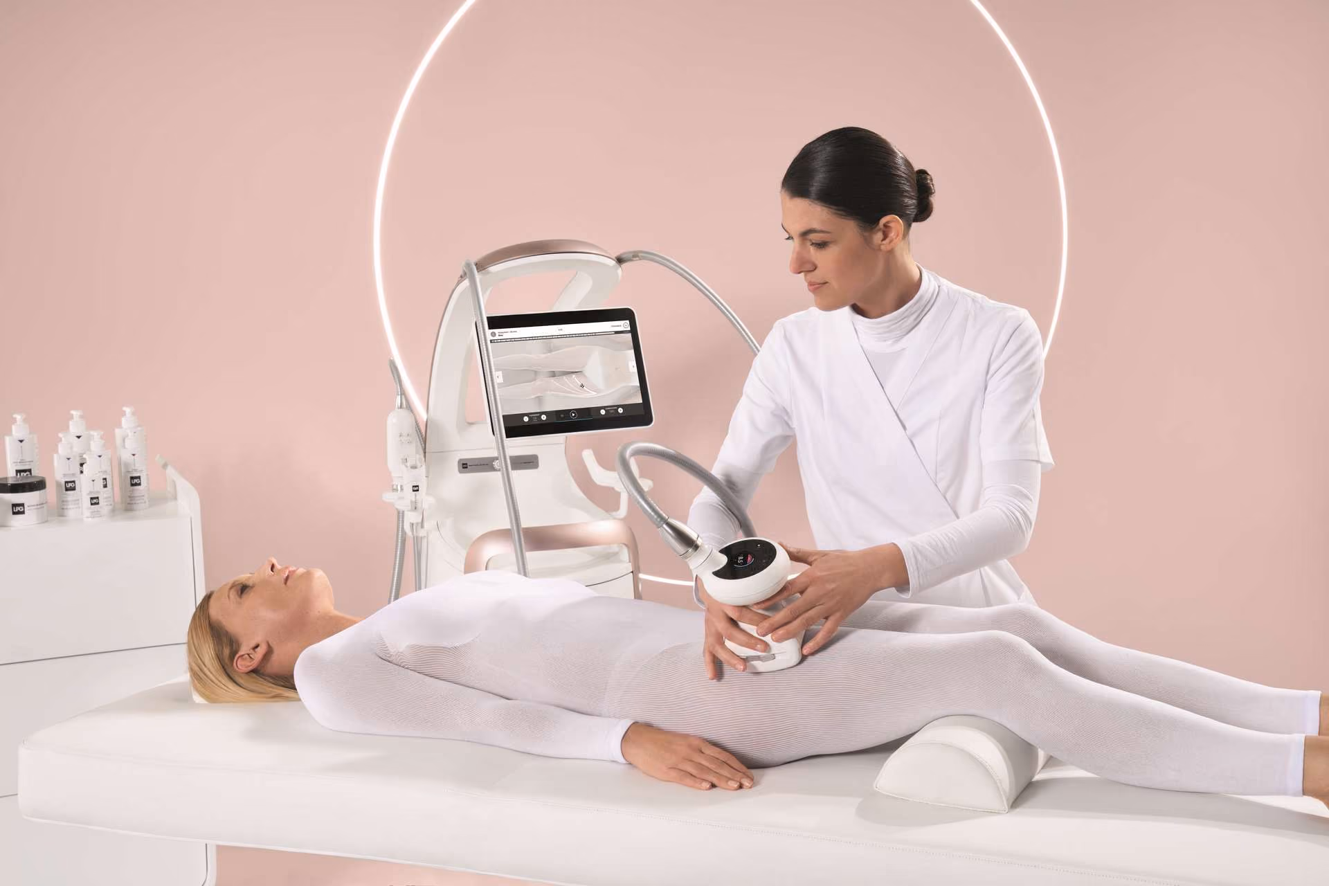 Therapist performing body treatment on a woman lying on a table in a skincare clinic.
