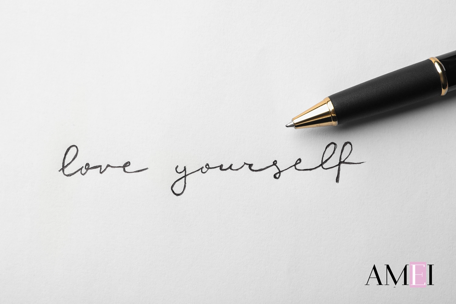 Frase 'love yourself' scritta a mano con penna su foglio bianco, concetto di auto-amore e scrittura terapeutica