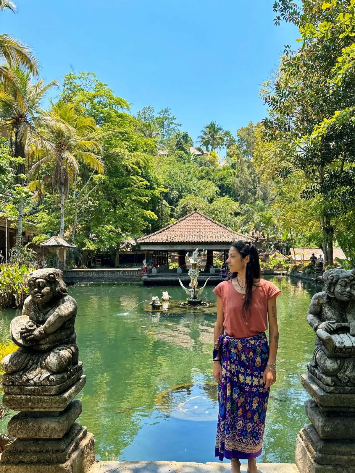 Jennifer Amadei immersa nella spiritualità di un tempio tradizionale a Bali, tra natura lussureggiante e atmosfere sacre