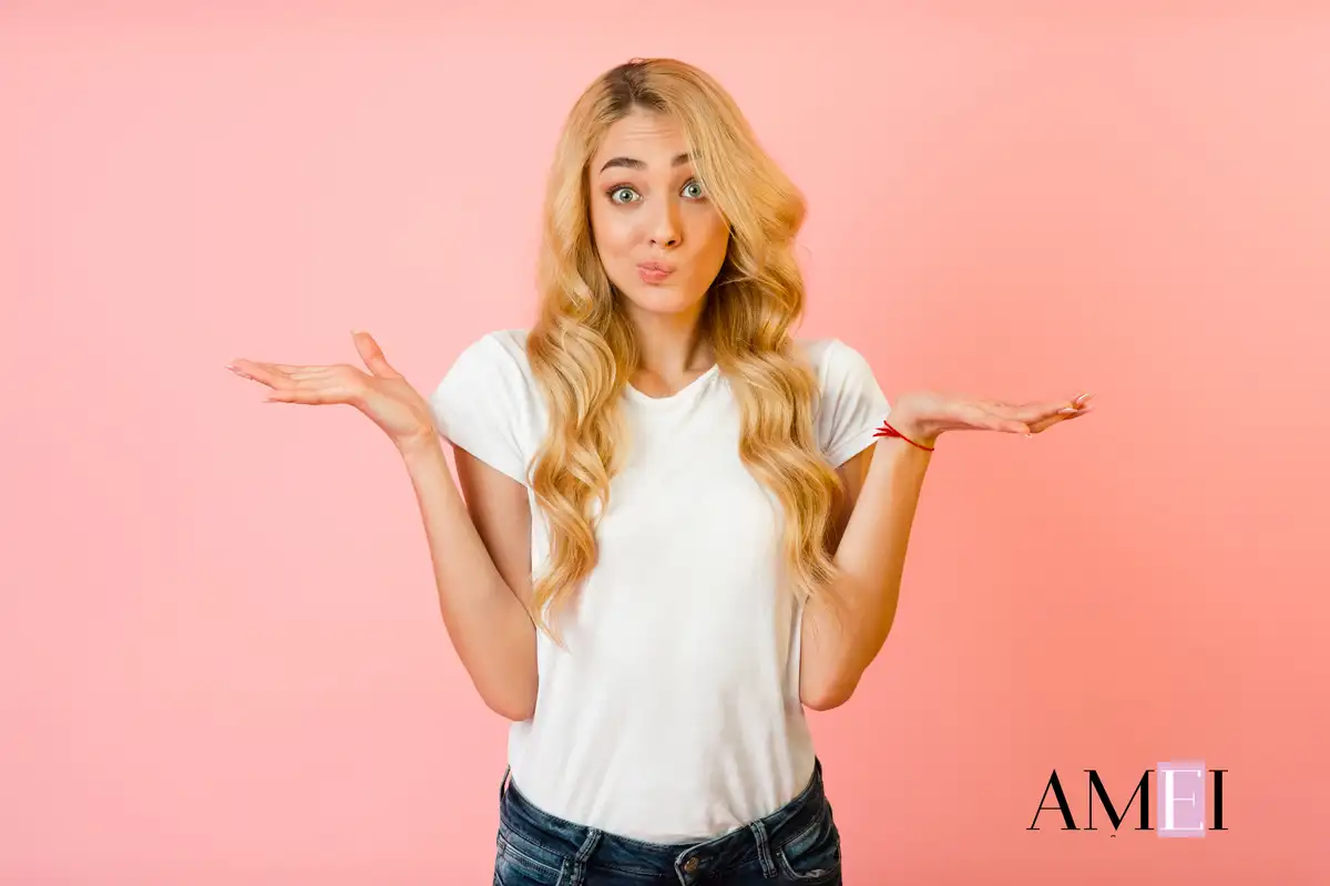 Donna bionda con espressione dubbiosa su sfondo rosa, concetto di scelte beauty e skincare su Amei Magazine  sql Copia Modifica