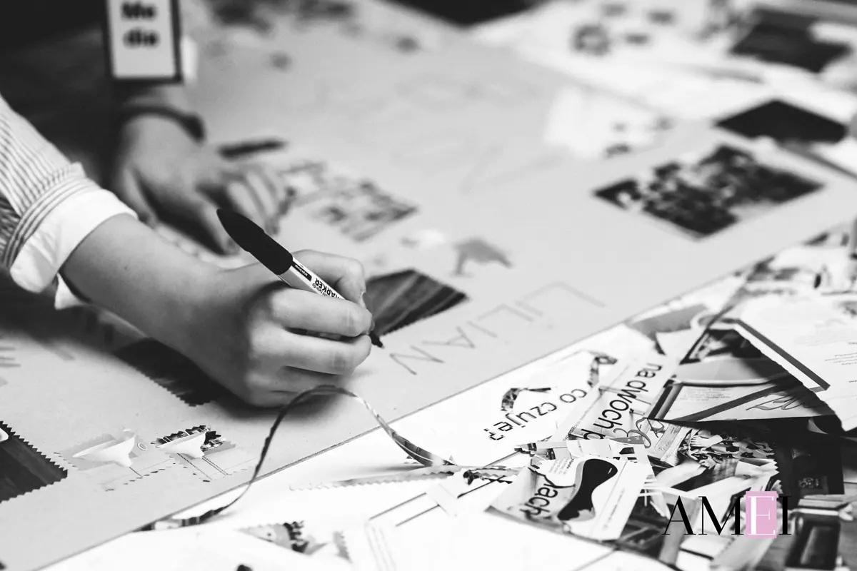 Mani che scrivono su un cartellone durante un laboratorio di collage creativo in bianco e nero