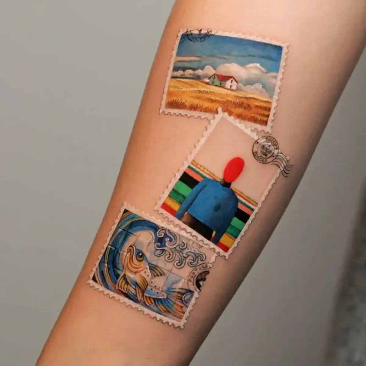Tatuaggio microrealismo con tre francobolli artistici colorati su avambraccio