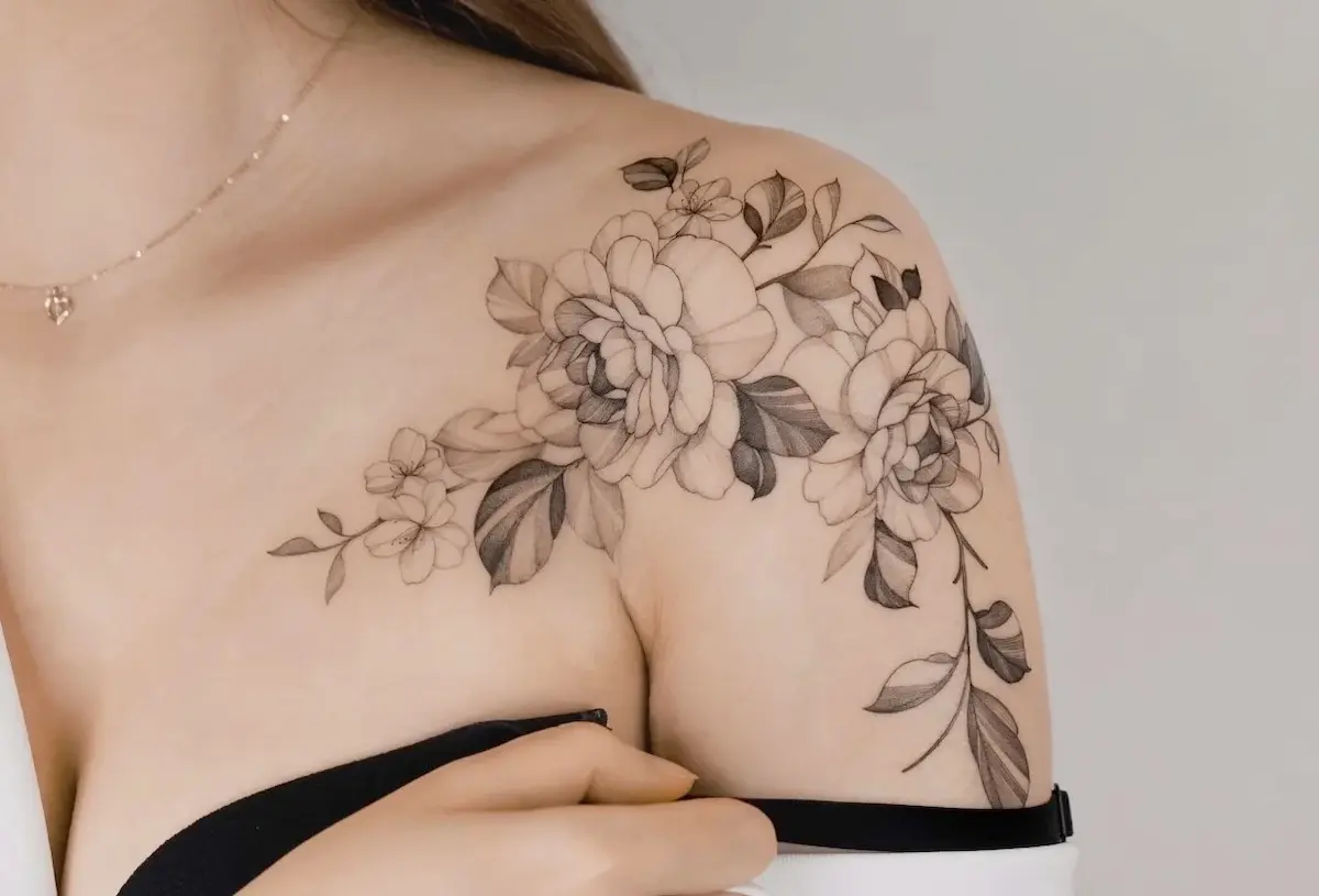 Tatuaggio floreale fine line su spalla femminile, design delicato in bianco e nero