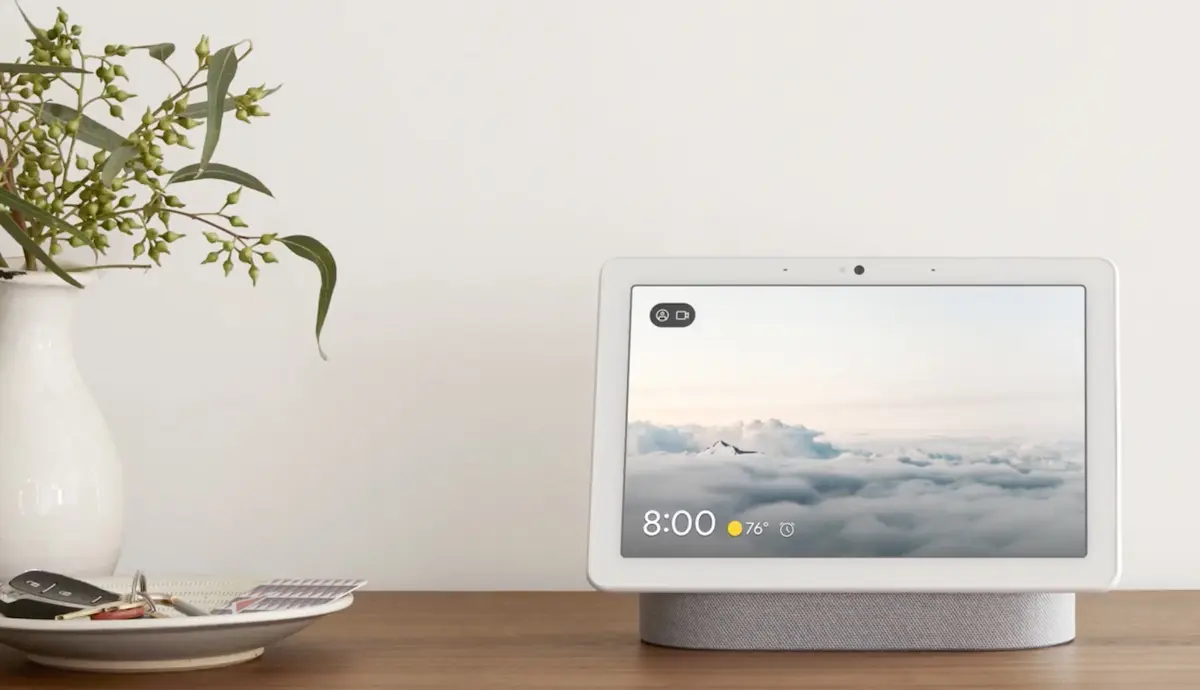 Google Nest Hub su tavolo in legno con schermo smart display acceso e design minimalista