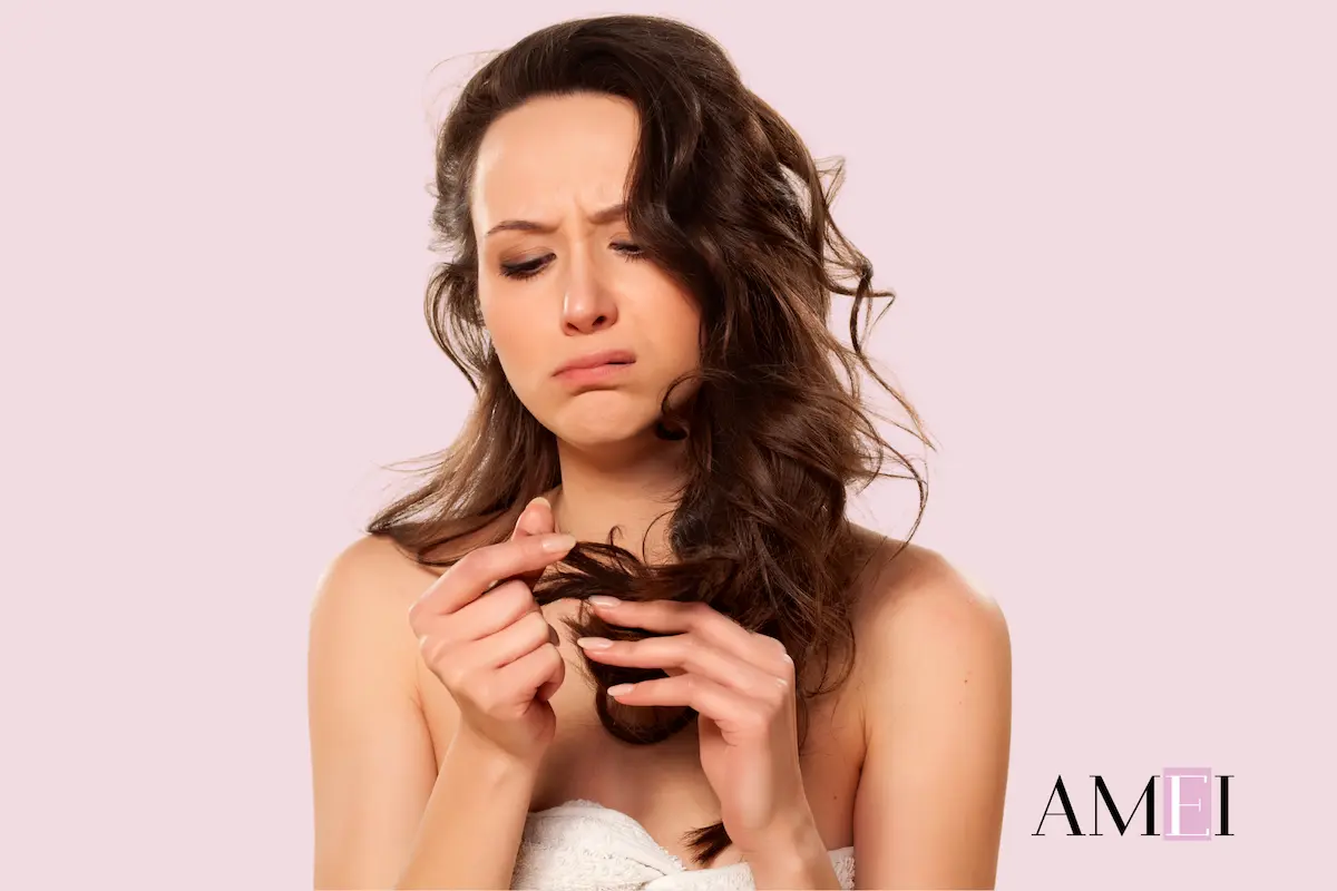 Donna con capelli danneggiati dopo le vacanze che osserva le punte sfibrate, cura capelli post sole e mare.