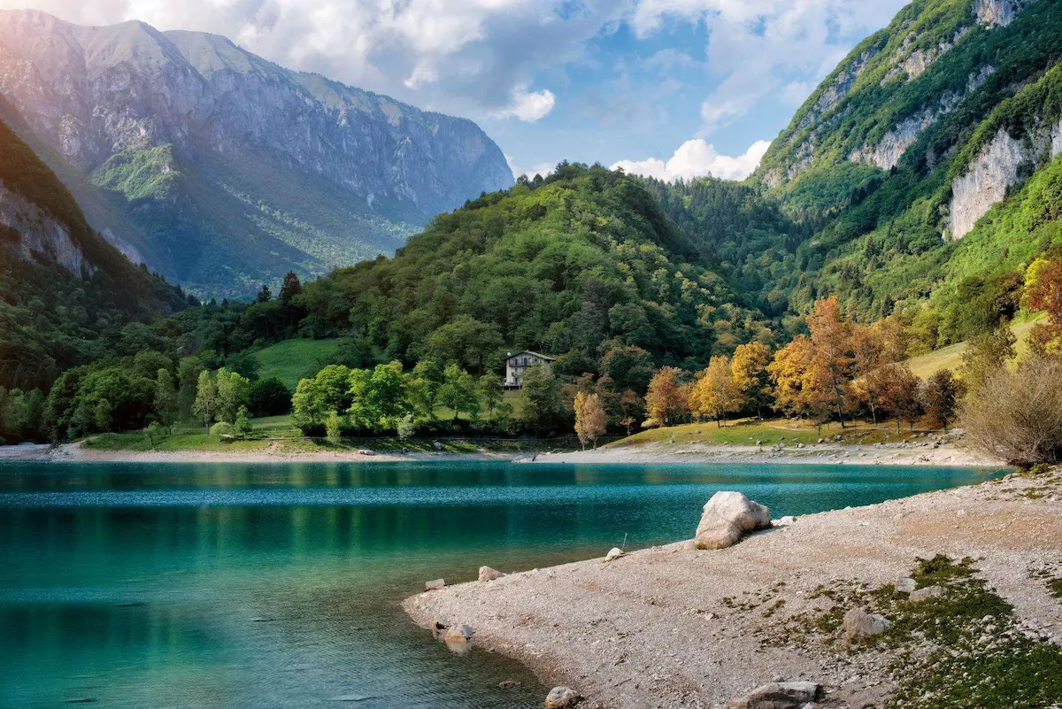 Lago di Tenno in Trentino con acque turchesi, boschi verdi e montagne alpine sullo sfondo