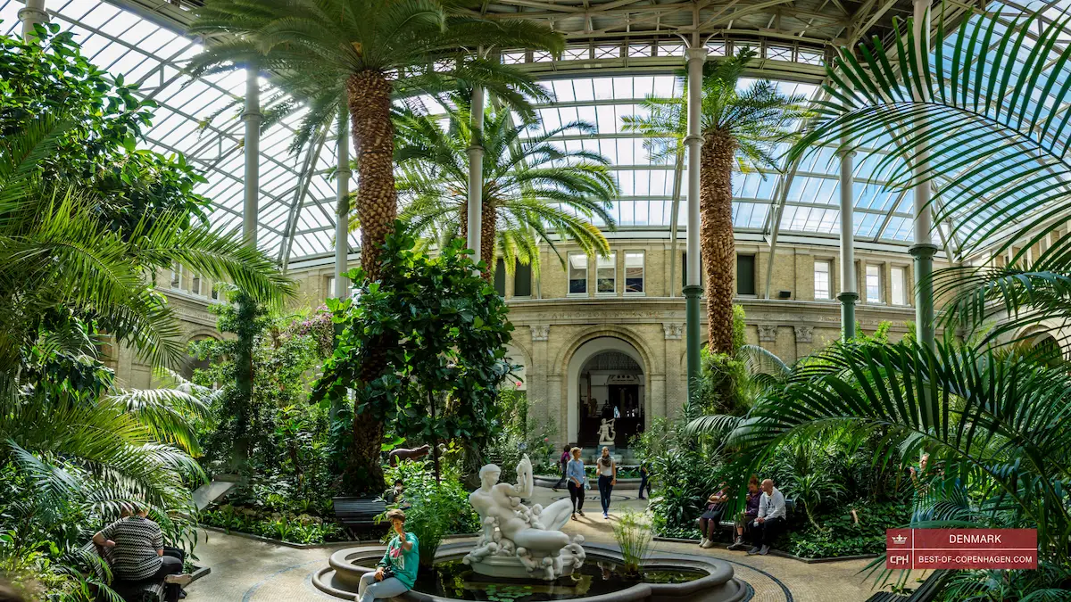 Giardino d’inverno del museo Glyptoteket a Copenaghen con palme, statue e visitatori