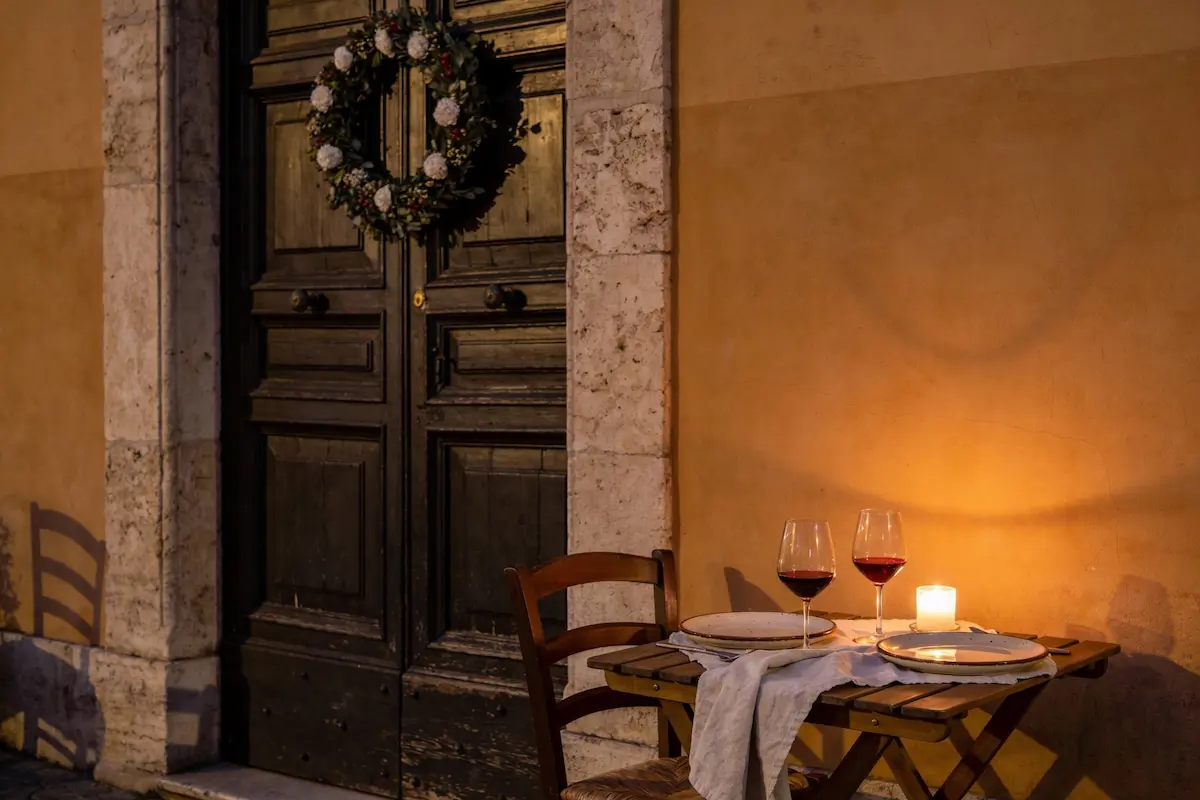 Tavolo apparecchiato in una trattoria di Roma in inverno con pasta, vino rosso e luce calda