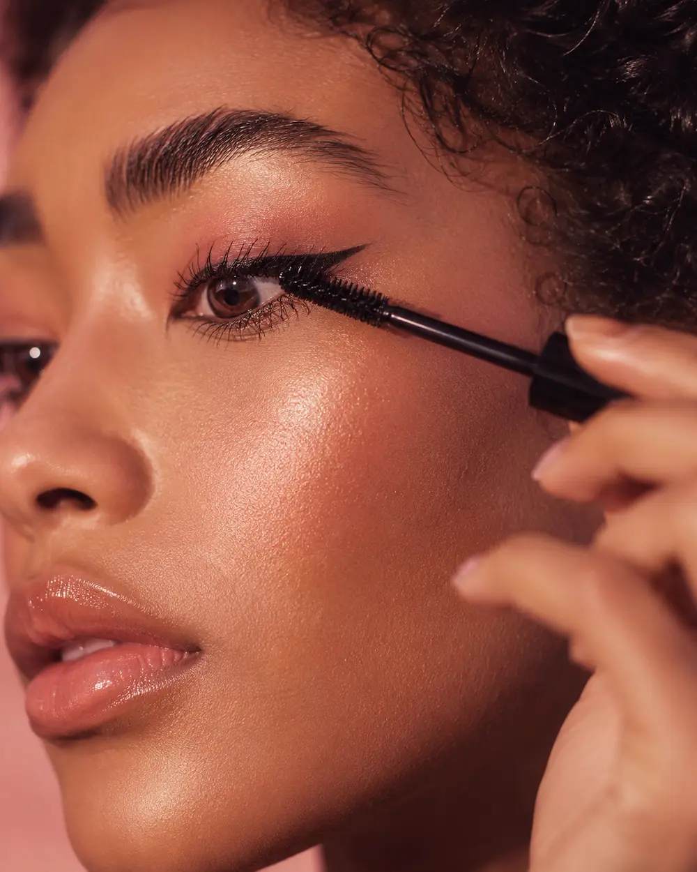 Donna applica il mascara su un occhio con eyeliner e sopracciglia definite
