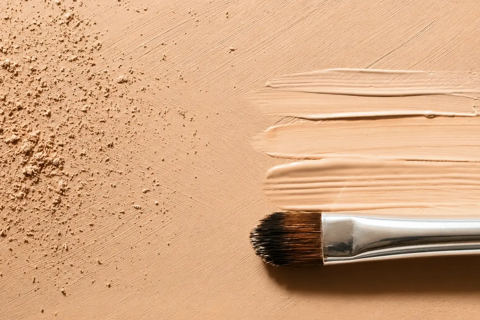 Texture di BB cream sfumata con pennello su fondo beige, base viso naturale con finish luminoso