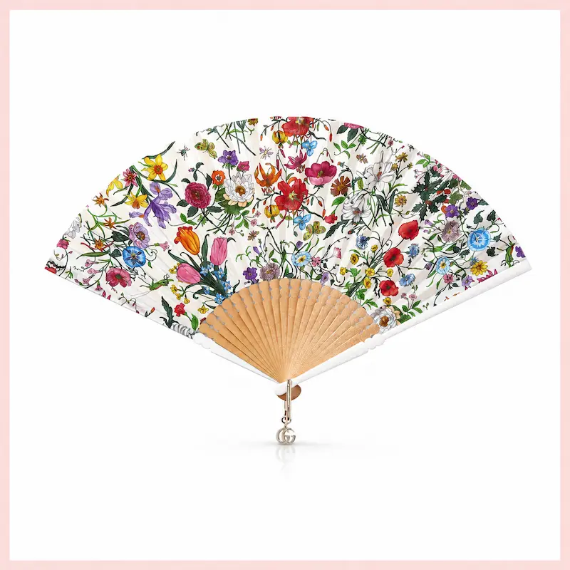 Ventaglio Gucci con stampa Flora multicolore e stecche in legno, accessorio moda di lusso per l’estate 2026.