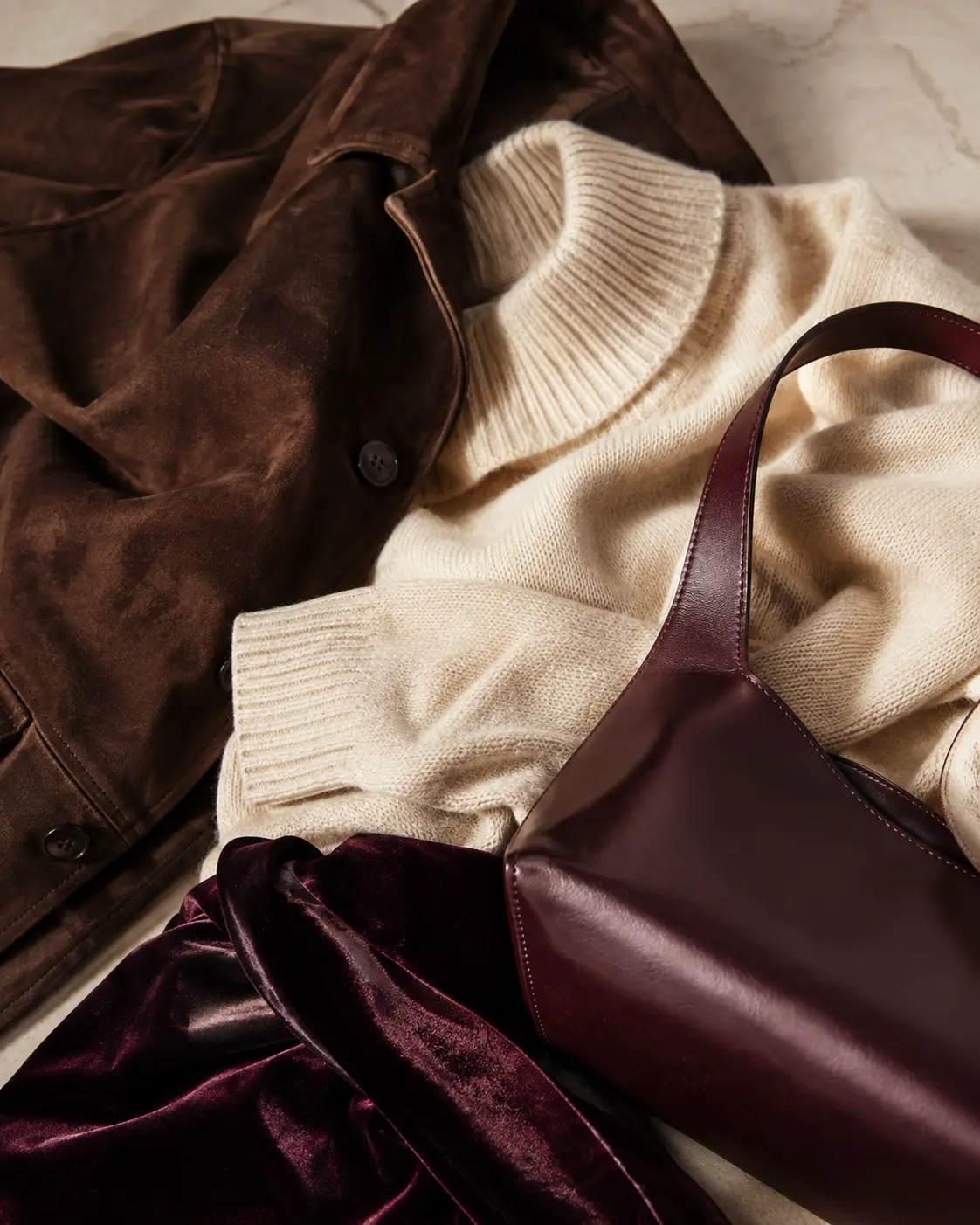 Giacca in suede marrone, maglia panna e accessorio in pelle borgogna