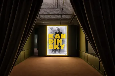 Ingresso della mostra Kandinsky a Palazzo Bonaparte, Roma, con sipari aperti e installazione luminosa all’entrata.