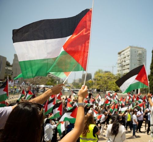 A crowd of people waving Palestinian flags during a Nakba commemoration ceremony at Tel Aviv University.