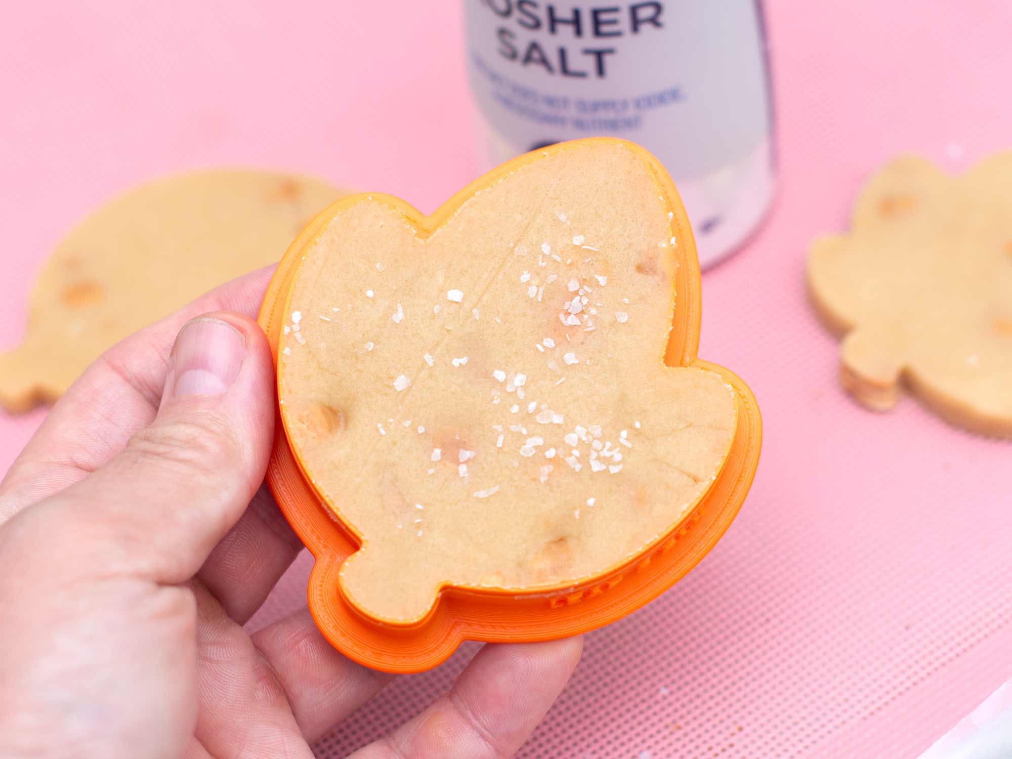 salting the bottom of a salted caramel cutout cookie