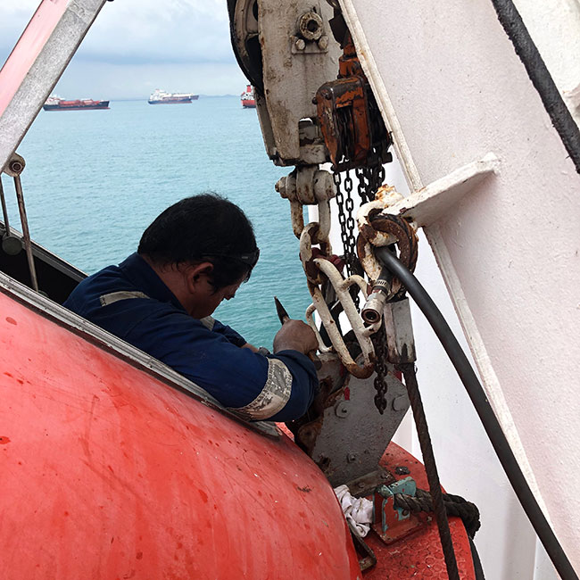 Technician chipping on lifeboat release hook