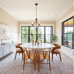 Bright modern dining room with a round white table, four mid-century style chairs, a black chandelier, and large black-framed windows overlooking greenery.