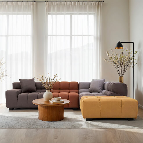 Modern modular sofa in a stylish living room with large sheer-curtained windows, a round wood coffee table, and warm neutral decor.