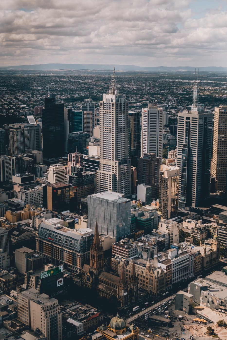 Aerial view of the Melbourne CBD skyline with skyscrapers under a cloudy sky