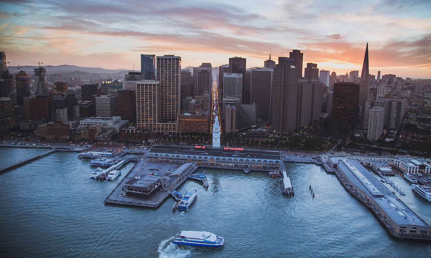 Aerial sunset view of San Francisco's Ferry Building, downtown skyline, and ferries on the bay