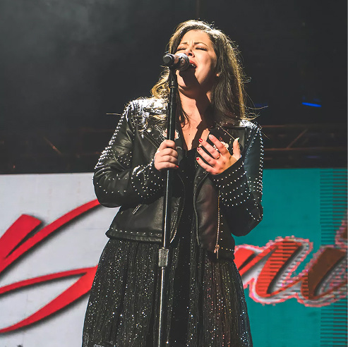 Female singer performing passionately under stage lights at a live concert event.
