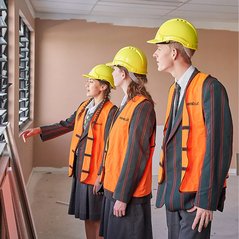 Students wearing hard hats during a supervised inspection tour of a construction site