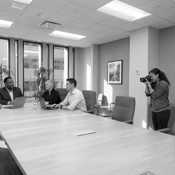 Photographer set up inside a boardroom to capture a team meeting in session around a table.