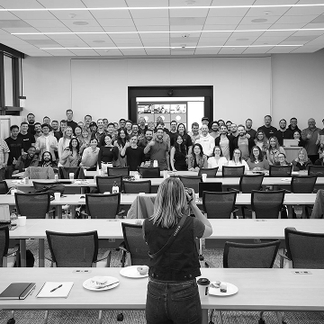 Photographer setting up to capture a large company group photo inside an auditorium.