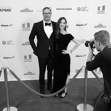Photographer capturing a formally dressed couple on a red carpet at a news media event.