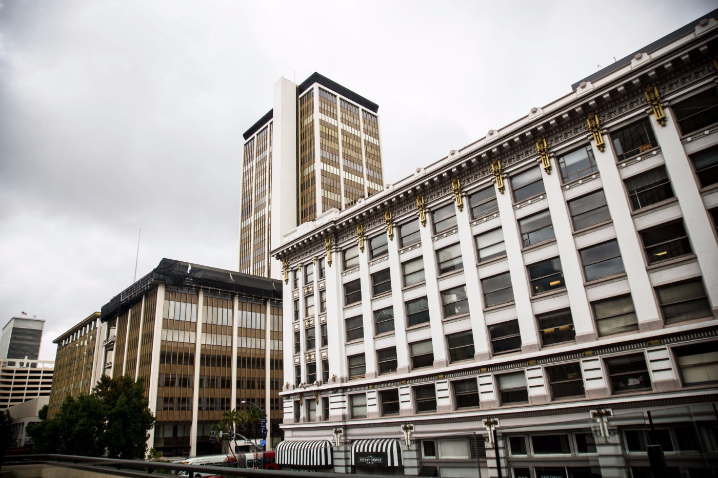 Downtown San Diego buildings including ornate historic facade and modern high-rise tower under cloudy sky