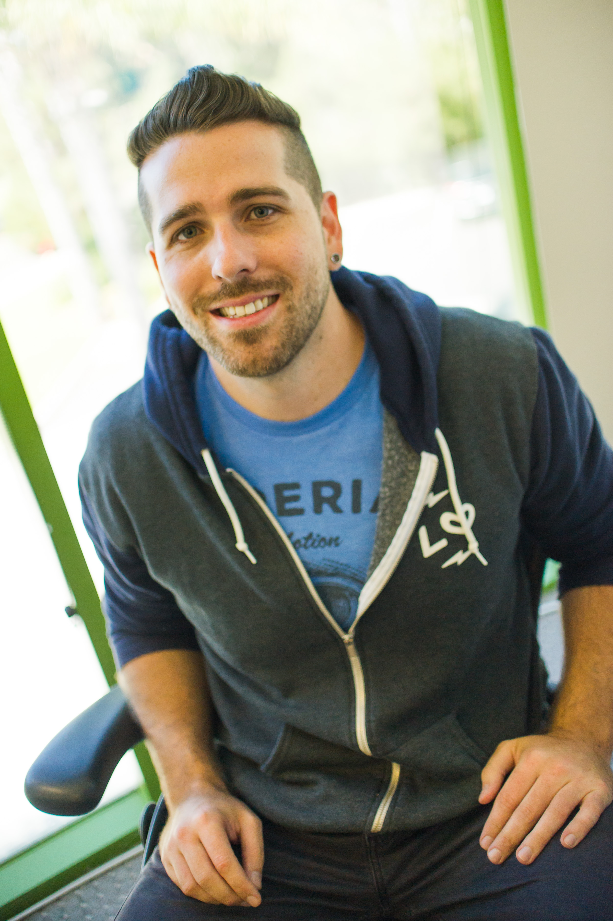 Lawn Love founder smiling in casual portrait wearing branded blue t-shirt and dark hoodie