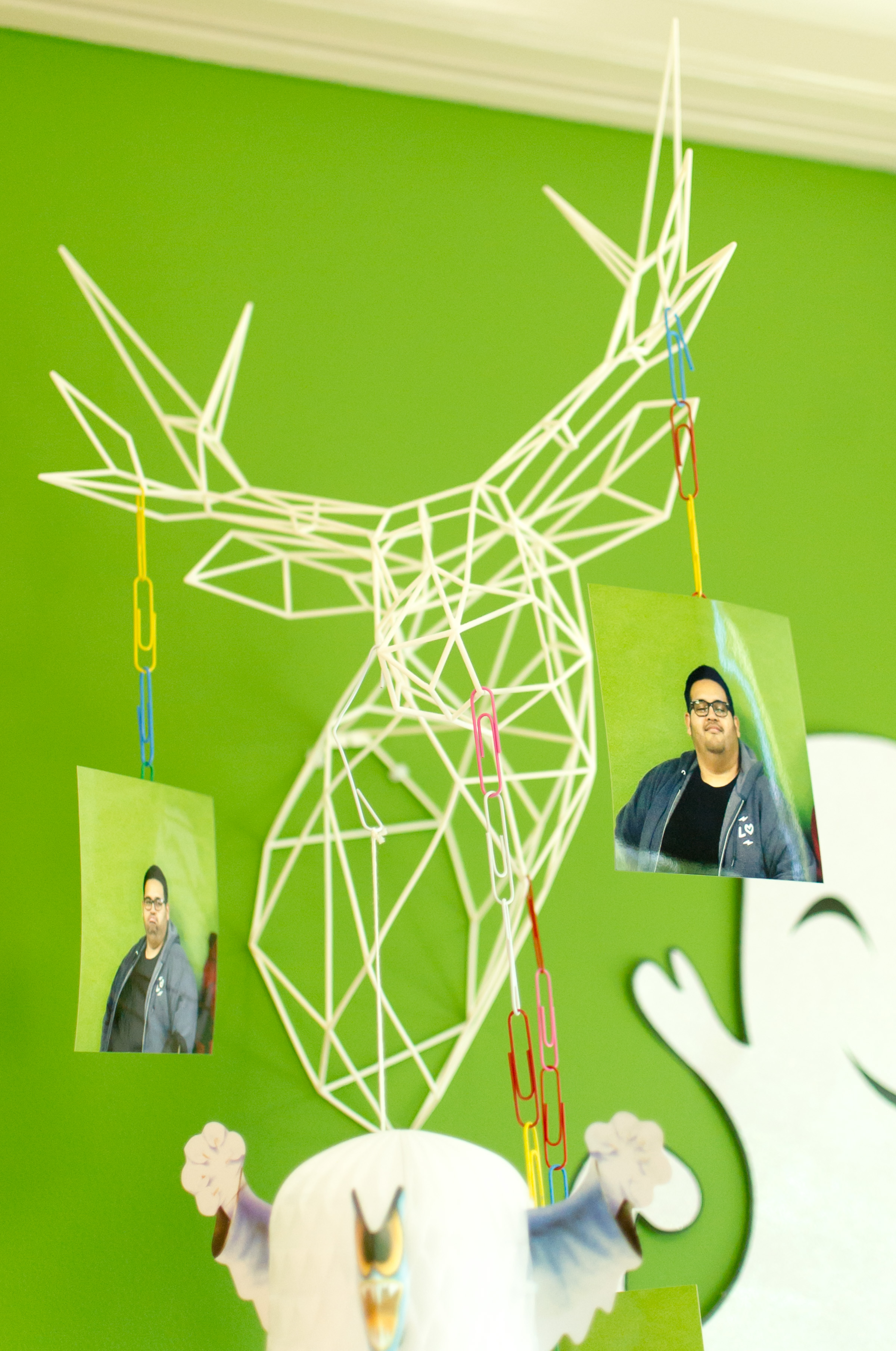 Wireframe deer head wall art with team member photos clipped to its antlers in the Lawn Love office