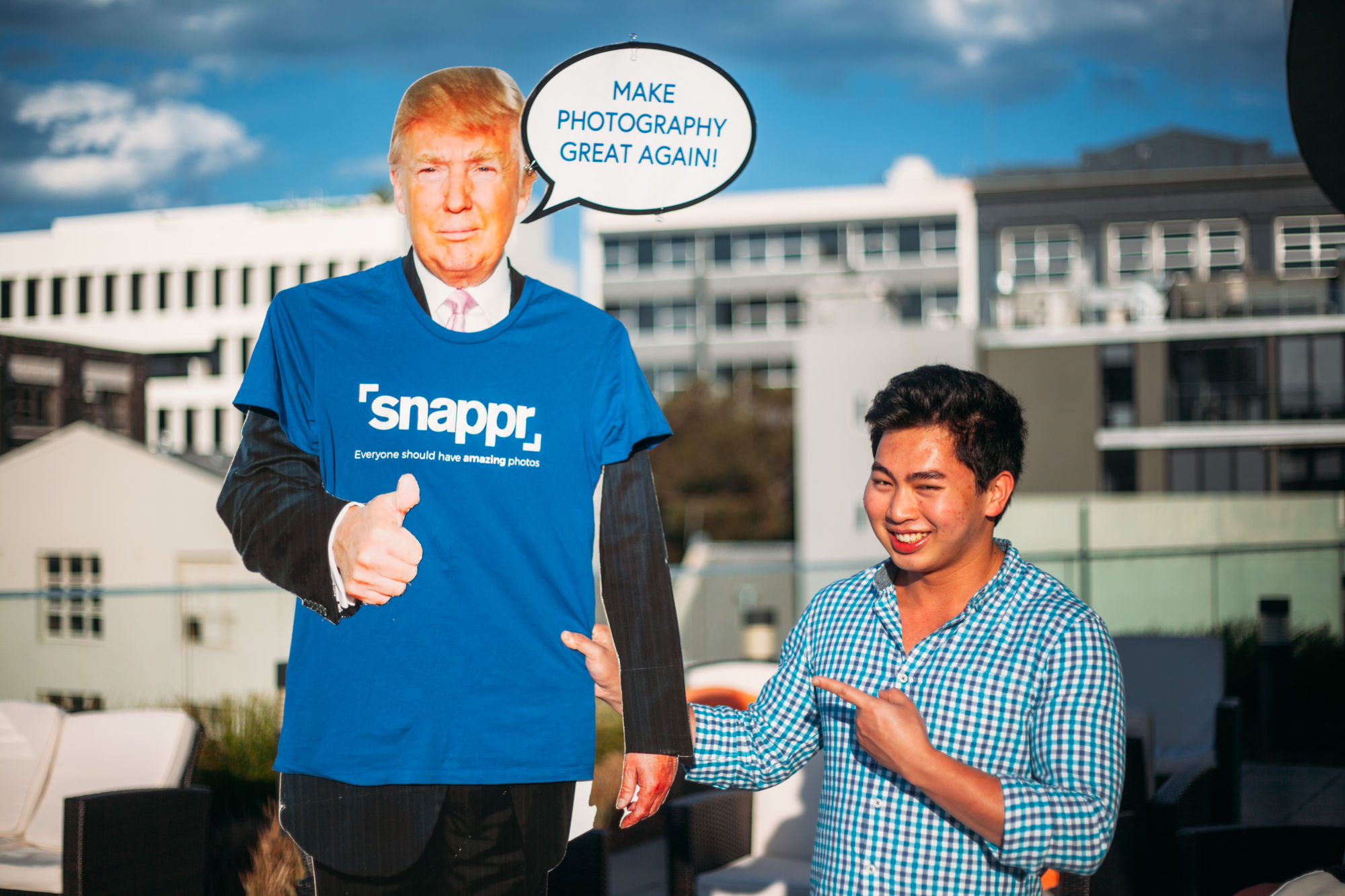Snappr team member posing with cardboard cutout wearing Snappr branded t-shirt at outdoor team event