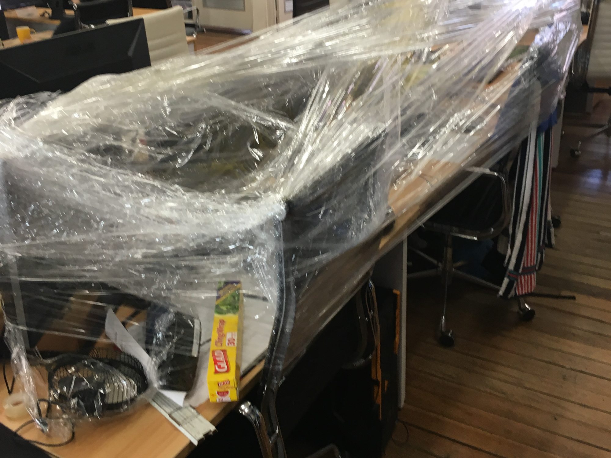 Snappr office prank - coworker's desk and computer wrapped entirely in plastic cling wrap