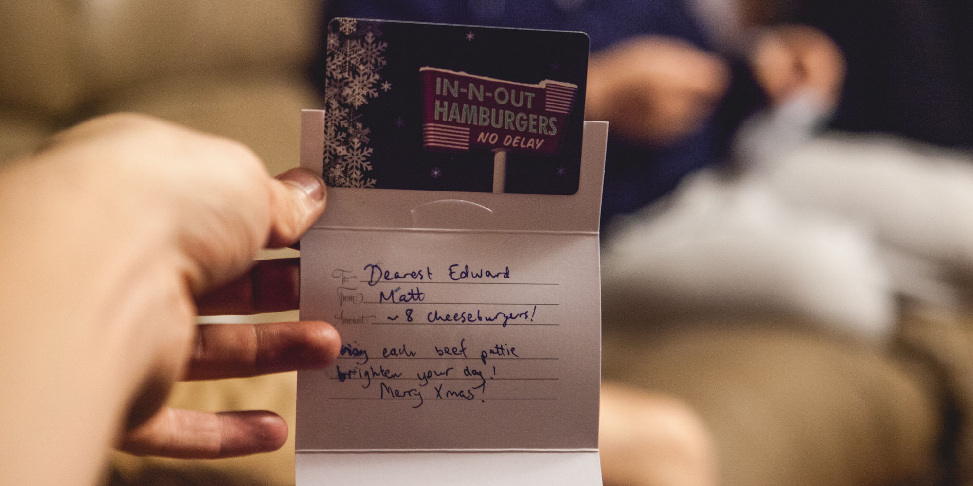 Hand holding handwritten Christmas card with In-N-Out Burger gift card from Snappr cofounder Matt to cofounder Edward