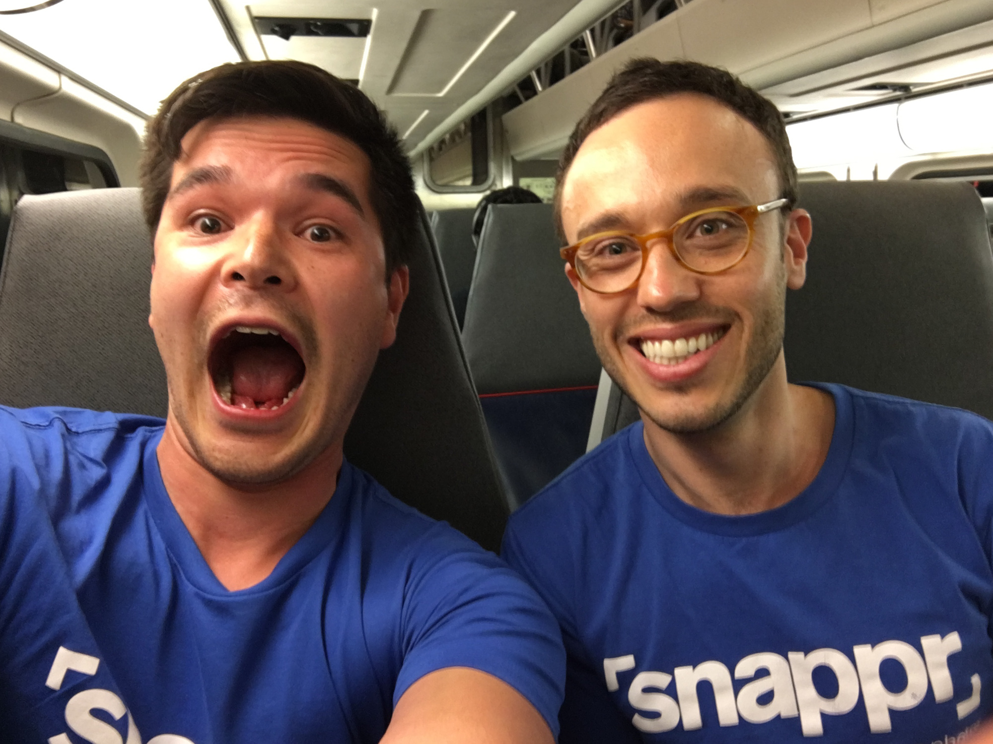 Two Snappr team members in branded blue t-shirts taking a fun selfie inside a vehicle