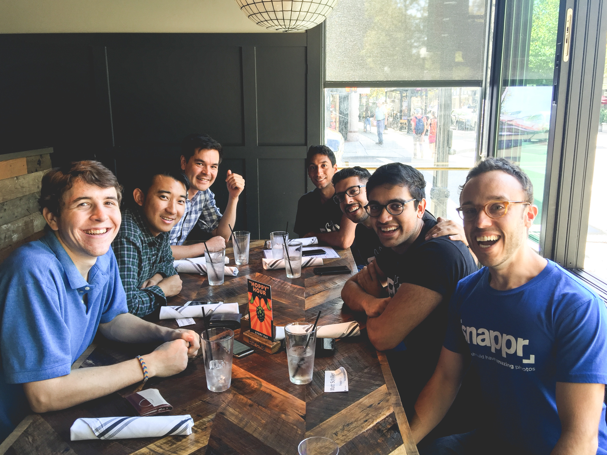 Snappr team enjoying happy hour drinks together at a restaurant with rustic wood table