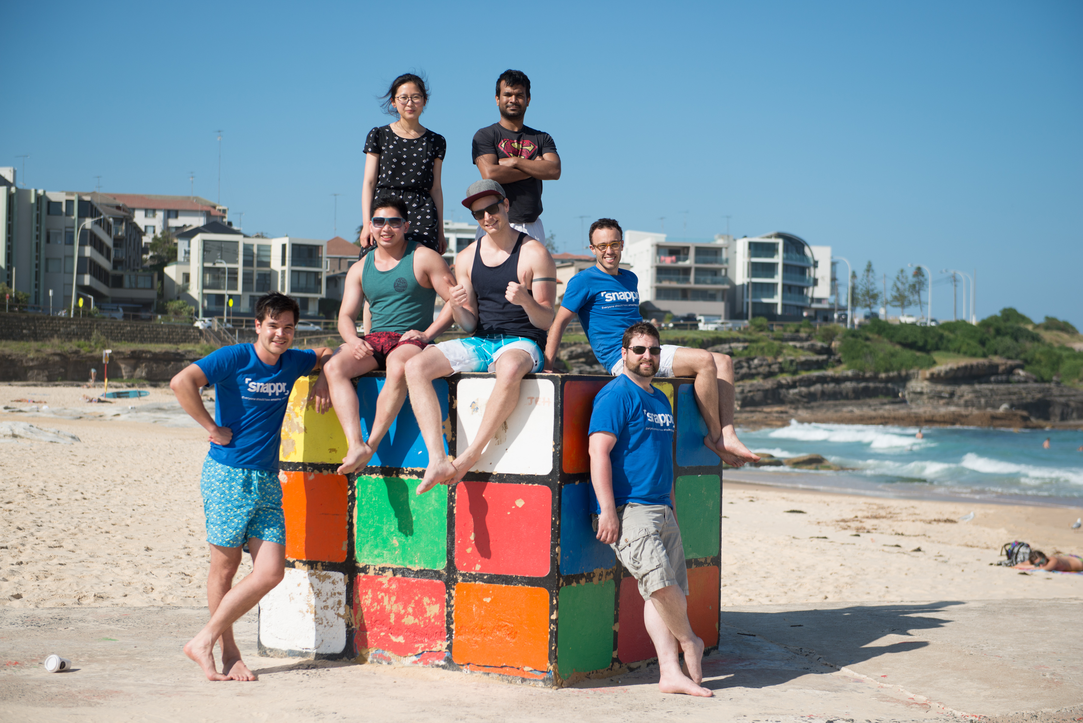 Snappr team posing on a giant Rubik's Cube sculpture at a Sydney beach