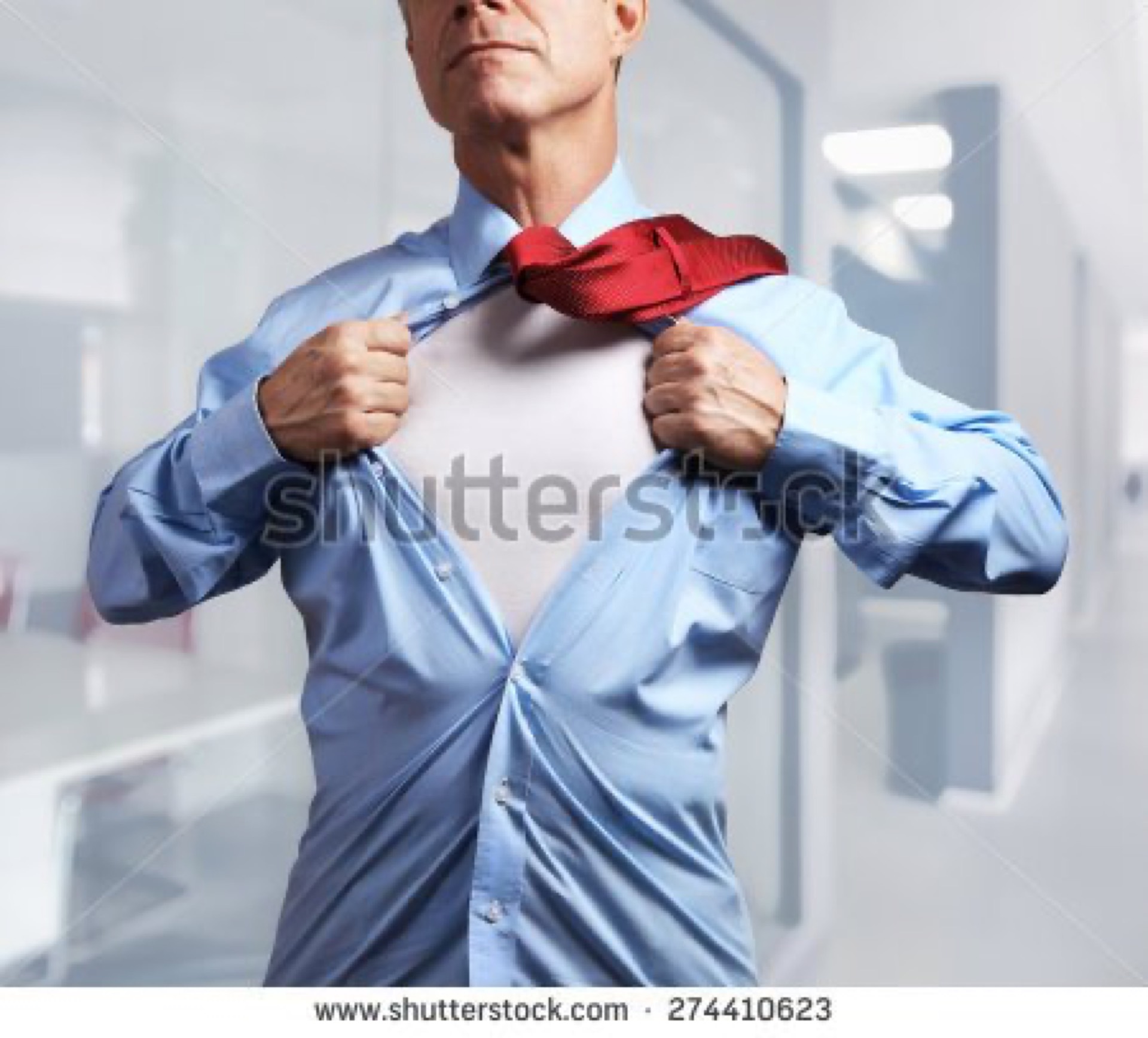 Senior businessman tearing open his shirt to reveal a superhero costume in an office corridor, a widely mocked overused corporate superhero stock photo cliche