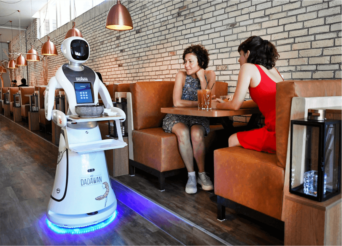 Dadawan restaurant robot server approaching two diners at a booth — automation and AI in the food service industry