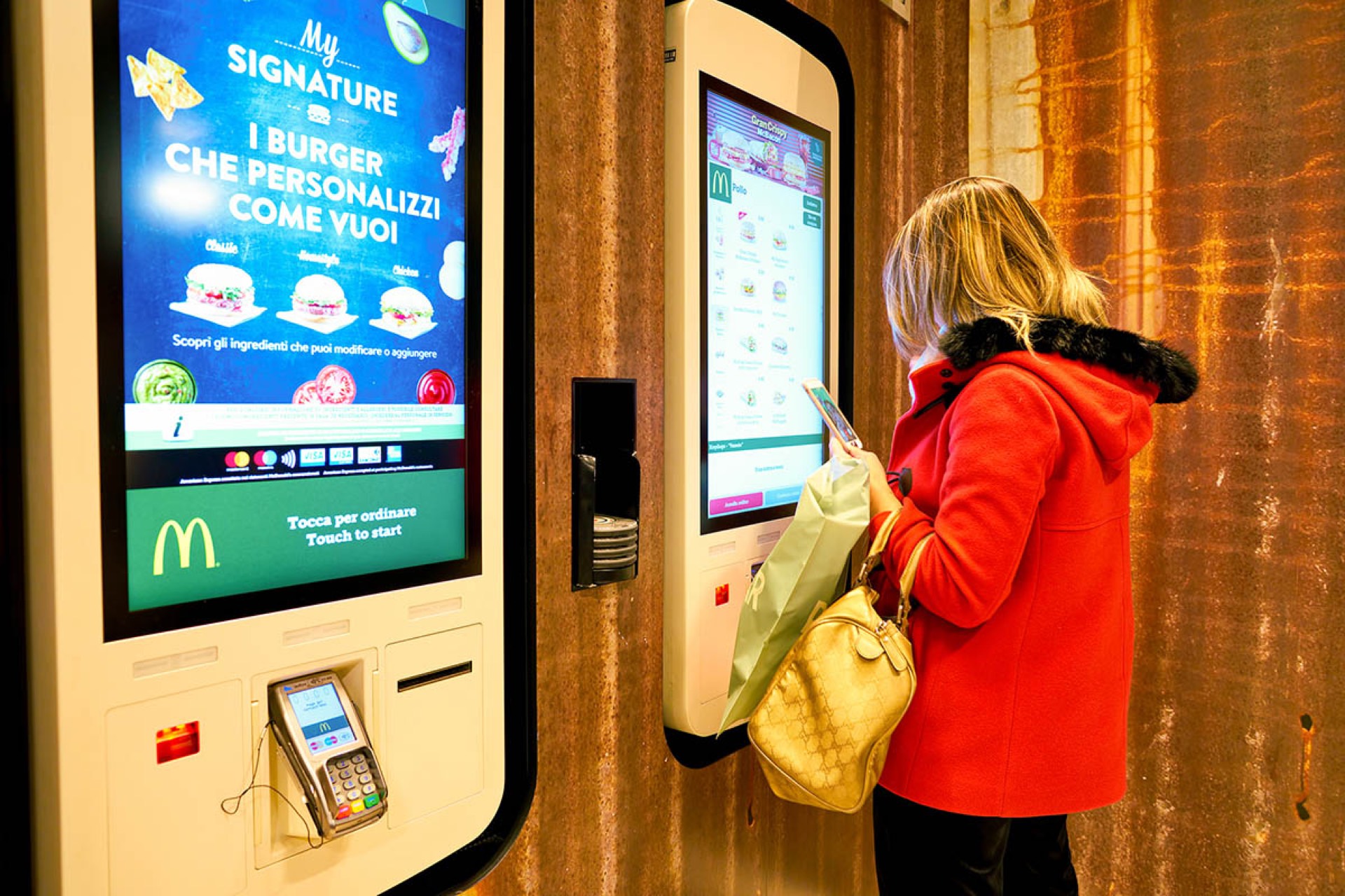 Customer using a McDonald's self-order kiosk touchscreen — self-checkout automation trend in the fast food industry