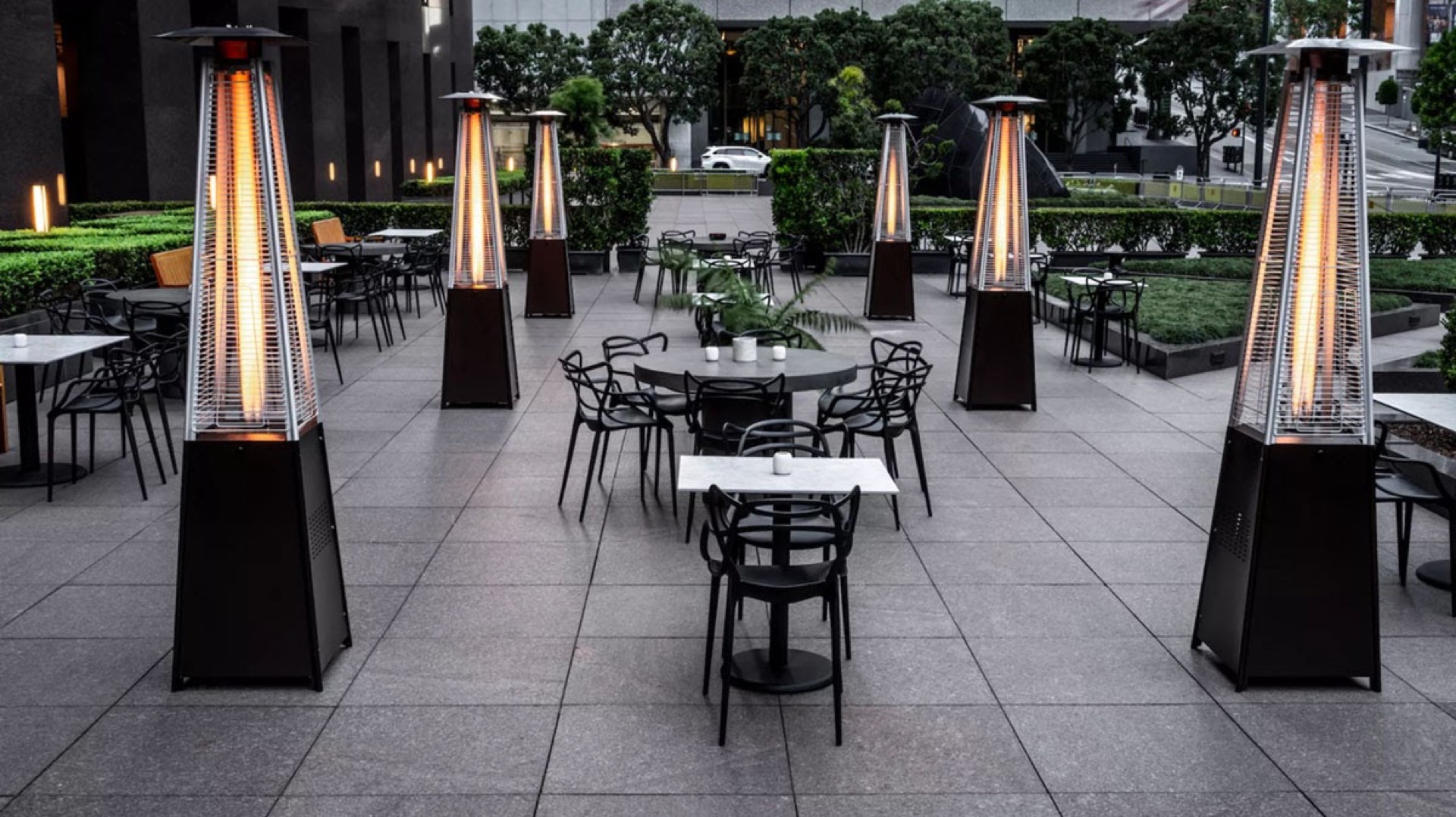 Upscale restaurant outdoor patio with pyramid heaters and black bistro chairs spaced for social distancing at dusk