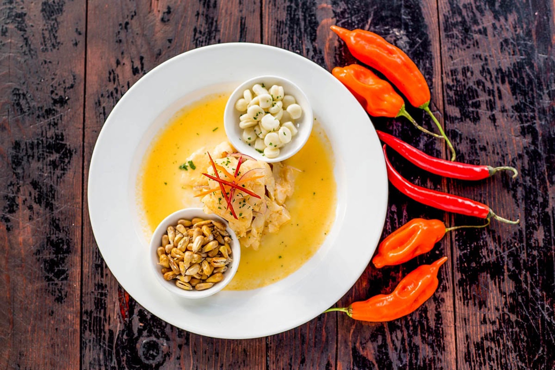 Ceviche dish on a white plate with chilli peppers and pumpkin seeds, styled for a Deliveroo food listing