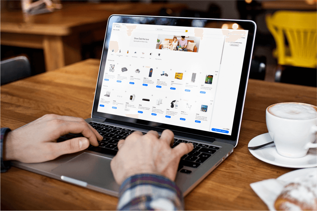 Person browsing an e-commerce product catalogue on a laptop at a café table, illustrating post-COVID retail shift