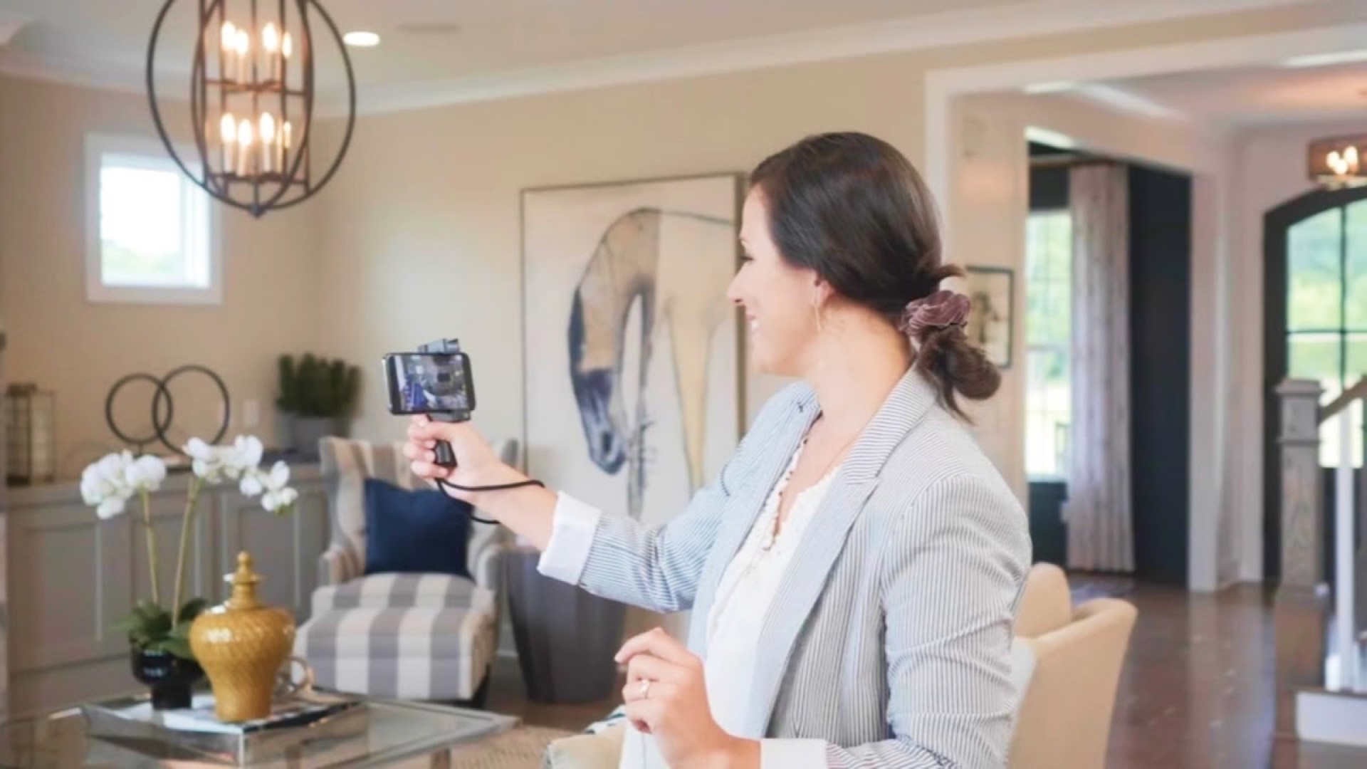 Real estate agent filming a home living room with a smartphone rig, illustrating new technology adoption in post-Covid property marketing